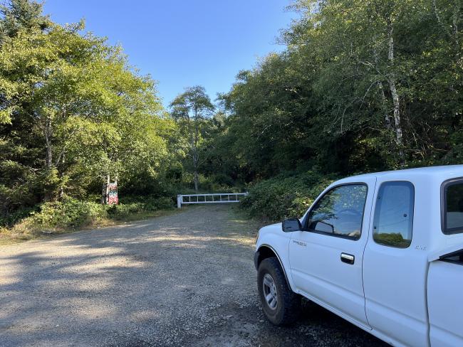 Truck parked at the side of the road with a gate in the background