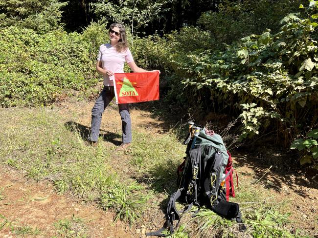 Myself holding a SOTA flag at the side of the gravel road